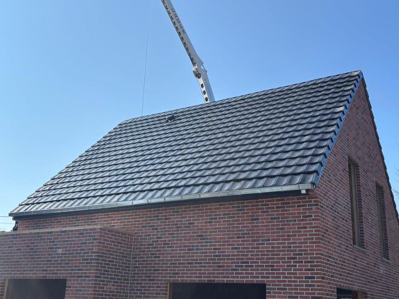 Pose d'une toiture en tuiles sur une maison en briques